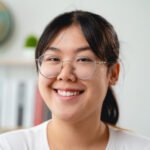 A portrait of young Asian woman wearing eyeglasses, smiling and